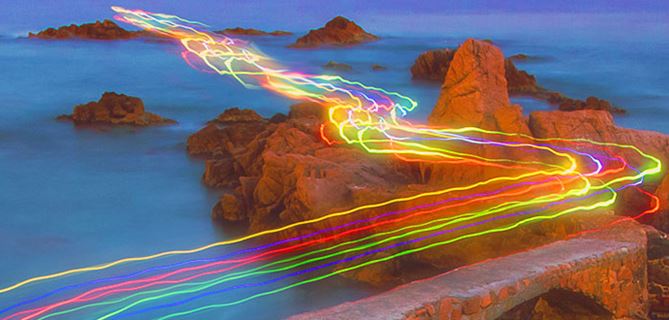 Road with colourful light trails at a body of water